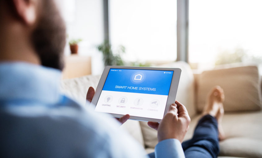 A man holding a tablet with smart home screen.