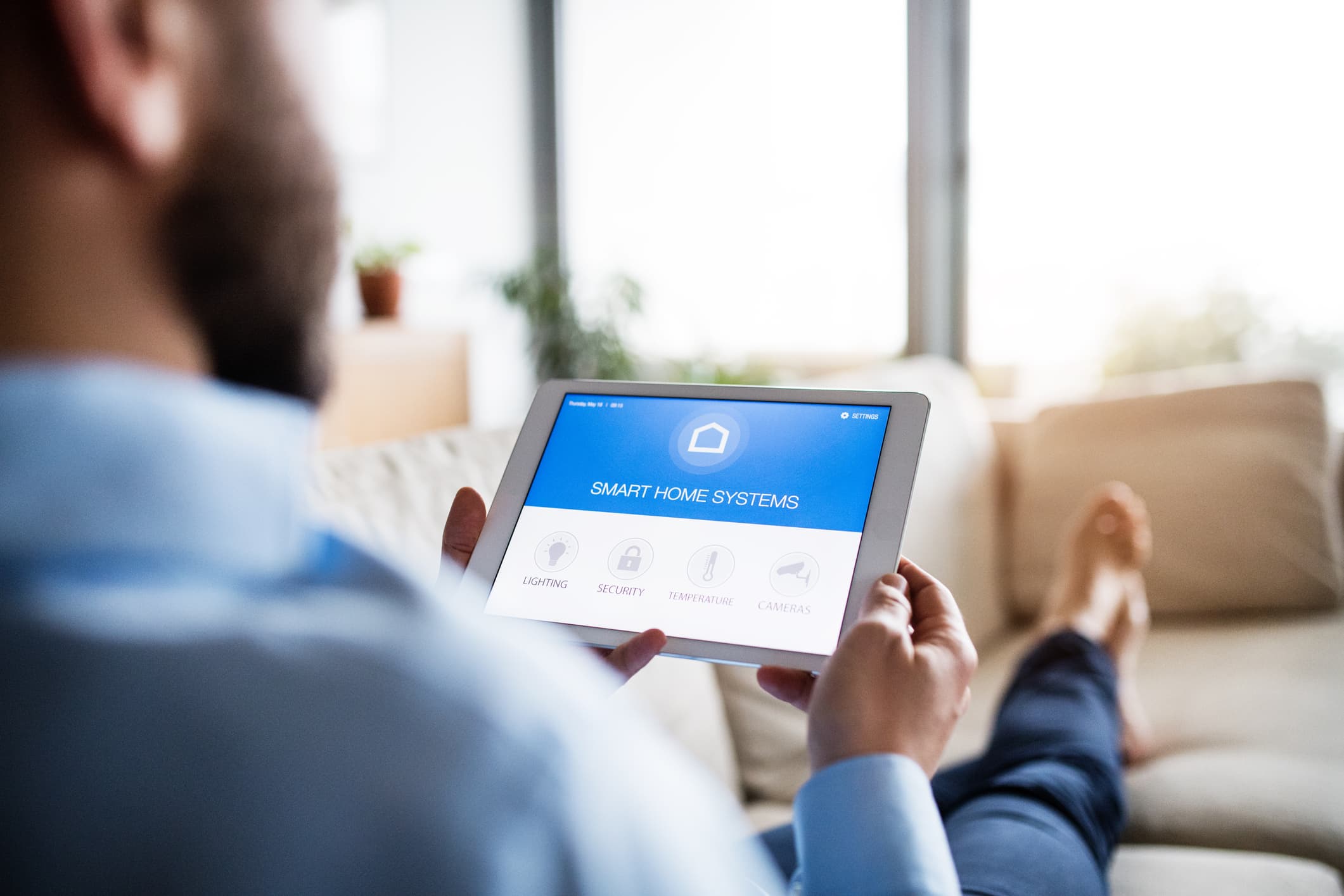 A man holding a tablet with smart home screen.