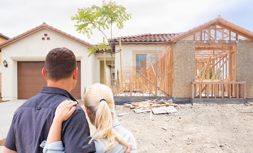 A couple facing a new custom home that is under construction.